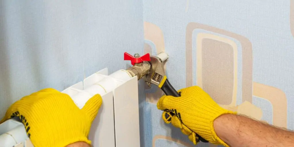 Técnico a purgar radiador frio para remover ar e restaurar aquecimento central